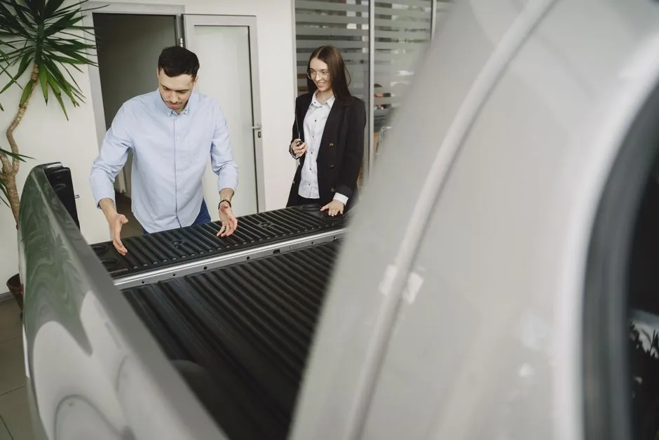 A buyer examining a pickup truck's bed in person before purchase, illustrative photo